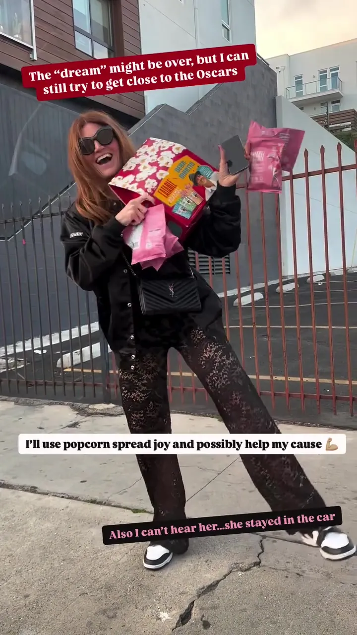 Kristin outside the Oscars fencing in LA, arms full of Eatable popcorn